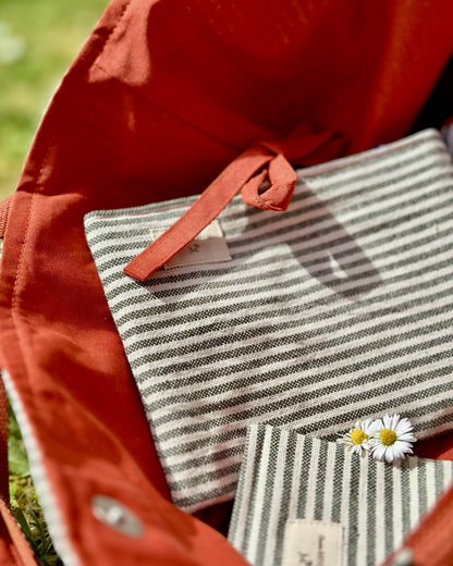 Détail pochette plate Deauville Safran glissée dans le maxi sac – rayures coton écru et kaki, nouette terracotta, étiquette Cousine Antoinette, fabriquée en France

